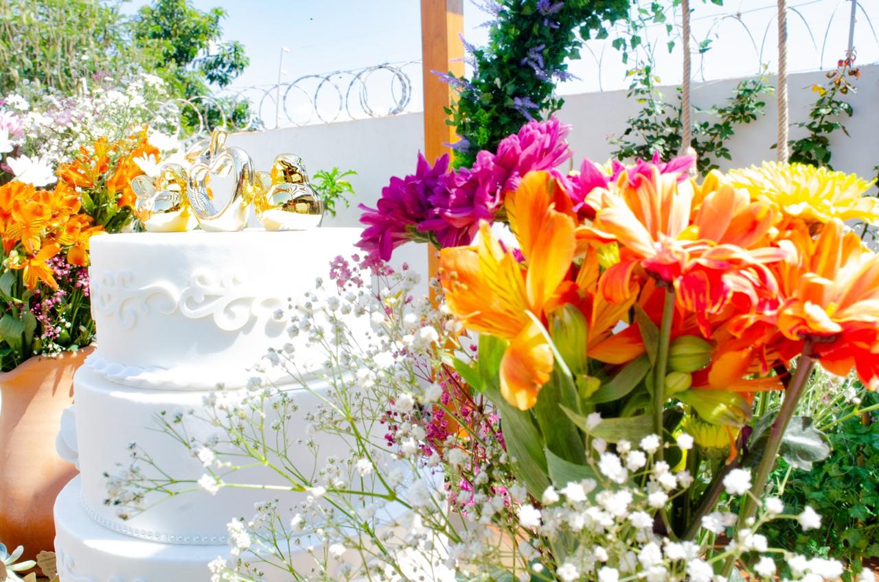 Detalhe do bolo de festa entre as flores no Recanto Boa Vida